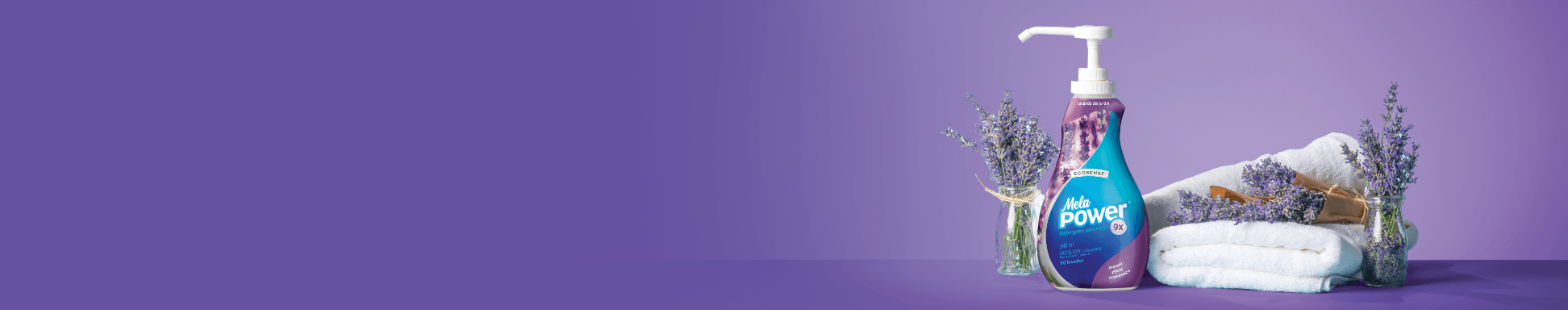 Botella de detergente líquido MelaPower 9x sobre un fondo morado, junto a flores secas y toallas blancas dobladas.