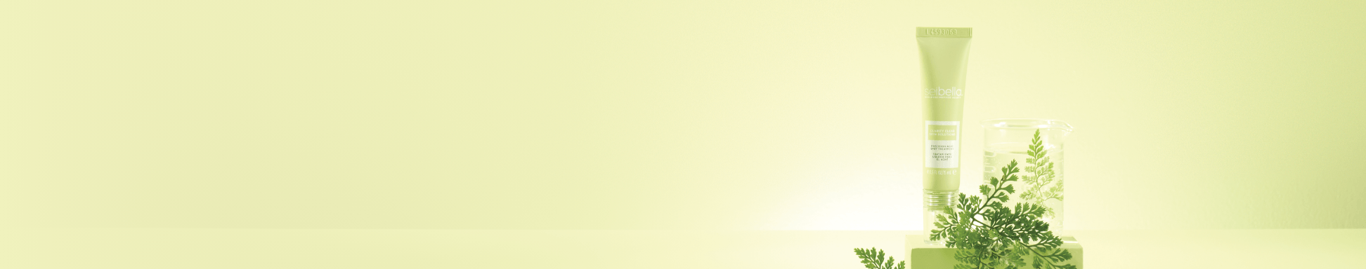 Tubo de crema facial Selbella sobre un fondo degradado en tonos amarillo verdoso, acompañado de hojas verdes en primer plano y un recipiente de vidrio desenfocado al fondo, con una estética fresca y natural.