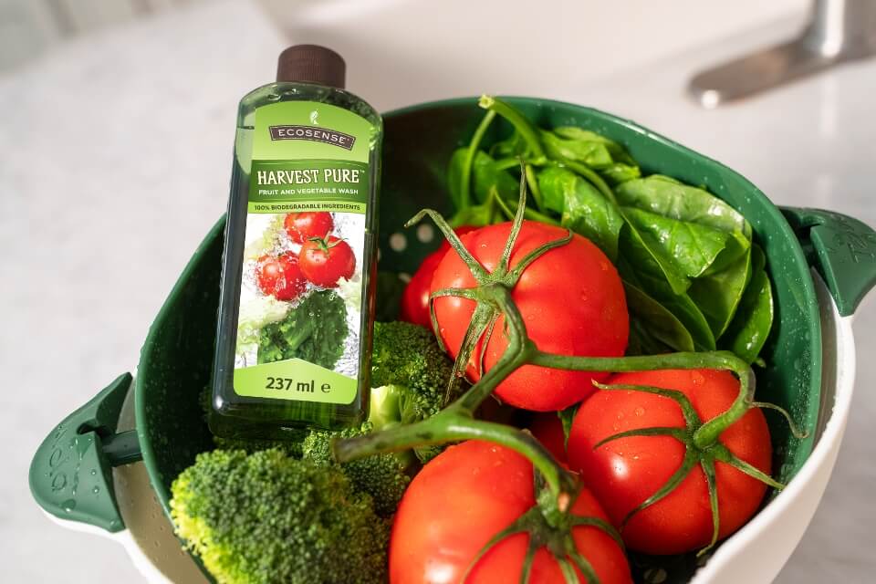 A bottle of Harvest Pure in a strainer bowl with some tomatoes and broccoli.