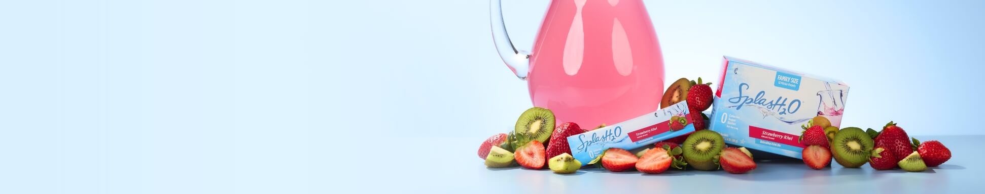 A clear pitcher filled with pink liquid is surrounded by sliced strawberries and kiwis. Two boxes labeled "SplasH20" accompany the fruit on a light blue background.