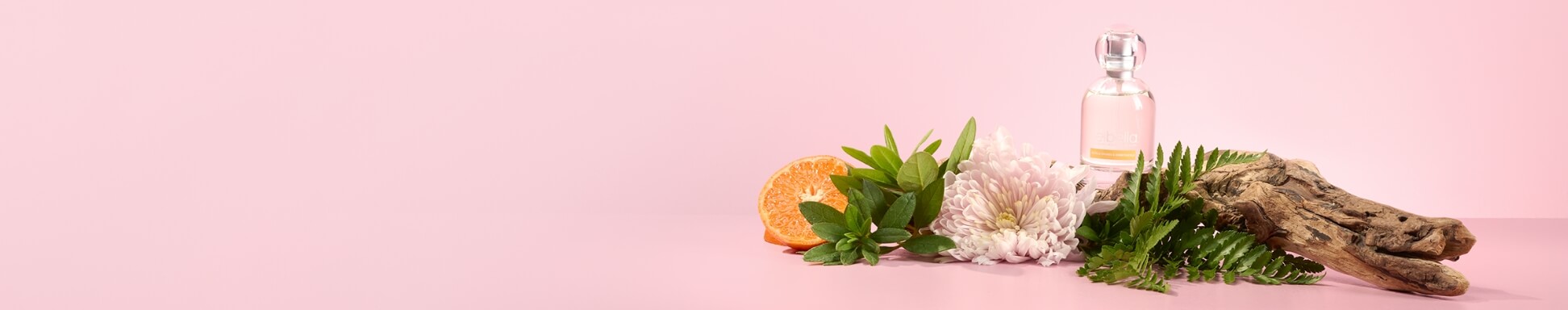Seville Orange & Honeysuckle perfume surrounded by florals, oranges, leaves and wood on a pink backdrop