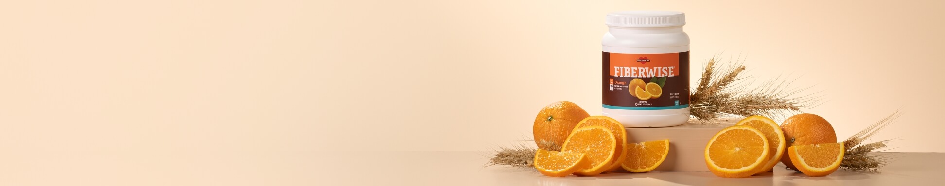 Fiberwise canister surrounded by oranges on a tan backdrop