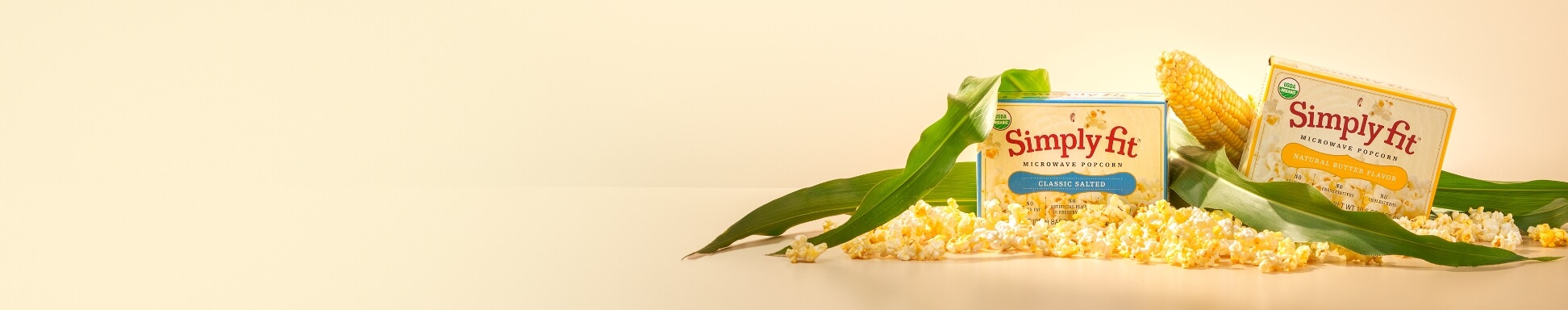 Two flavours of simply fit popcorn with corn plants and popped kernels 