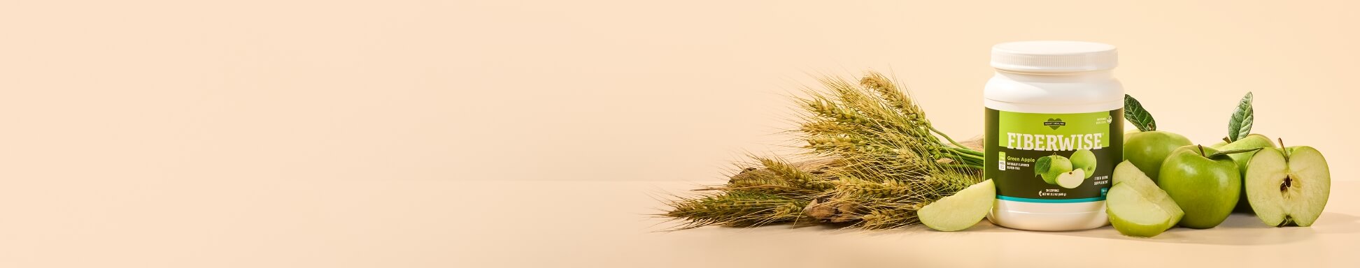 A canister of FiberWise, surrounded by wheat stalks and green apples.