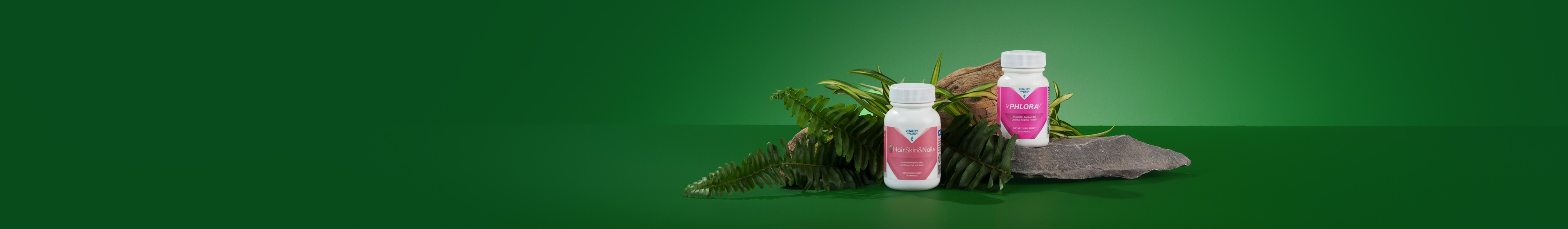 Two supplement bottles labeled "HairSkin&Nails" and "PHLORAV" on ferns and rocks, with a green background, creating a natural, healthy vibe.