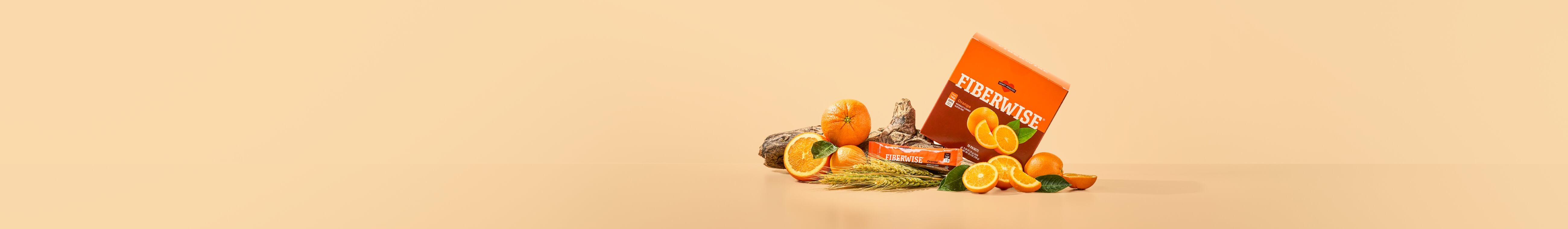A box of FiberWise packets surrounded by fresh oranges and wheat.
